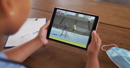 Poster - Composite of woman sitting at table with face mask, watching athletics running event on tablet