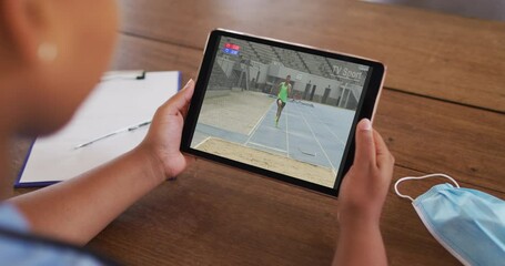 Poster - Composite of woman sitting at table with face mask, watching athletics long jump event on tablet