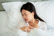 © Prot - Unhappy exhausted woman closed eyes lying in bed cause of Headache, sore throat and tired, Concept of recuperation from illness, feeling unwell and healthcare.
