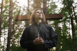 © M-Production - Christian priest with cross praying on the cemetery.