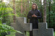 © M-Production - Christian priest with cross on the cemetery.
