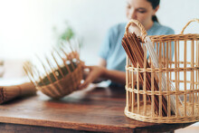 Woman Weaves Basket Of Paper Tubes On Wooden Table