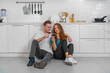 © Mongkolchon - couple sitting together on kitchen floor at home and drinking red wine