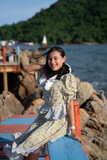 Fototapeta Londyn - portrait happy Asian woman tourist sit on colorful bridge with sea view at pagoda in the sea in windy day at Chantaburi, Thailand