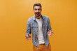 © Look! - Excited charming emotional man in blue checkered shirt and white t-shirt rejoices and looks into camera on orange background.