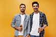 © Look! - Beautiful bearded young men in white t-shirts and checkered shirts pose on orange background and hold beer bottles.