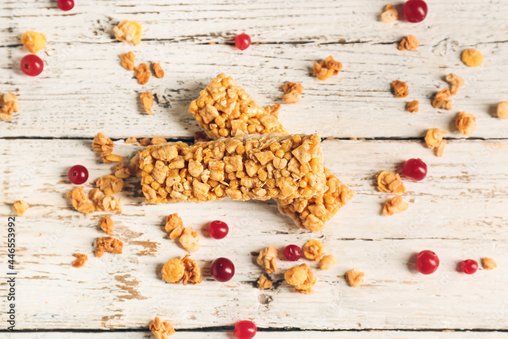 Healthy cereal bars and cranberries on light wooden background