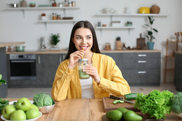 Sticker - Young woman drinking healthy green smoothie in kitchen