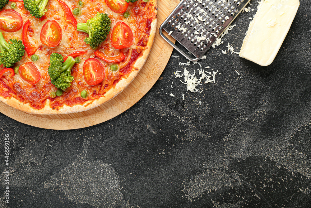 Board with tasty vegetarian pizza and grater on dark background