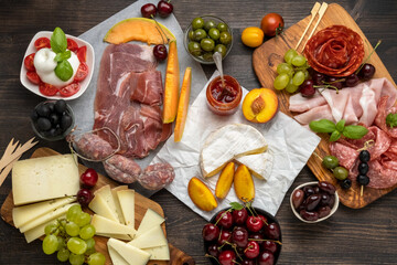  Festive Food for a christmas or thanksgiving or birthday party salami, parma ham, prosciutto with melon, pecorino and parmesan cheeses board, camembert cheese with red sauce and peaches grapes cherrie