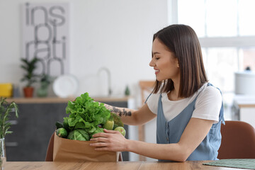 Wall Mural - Young woman with fresh vegetables in kitchen