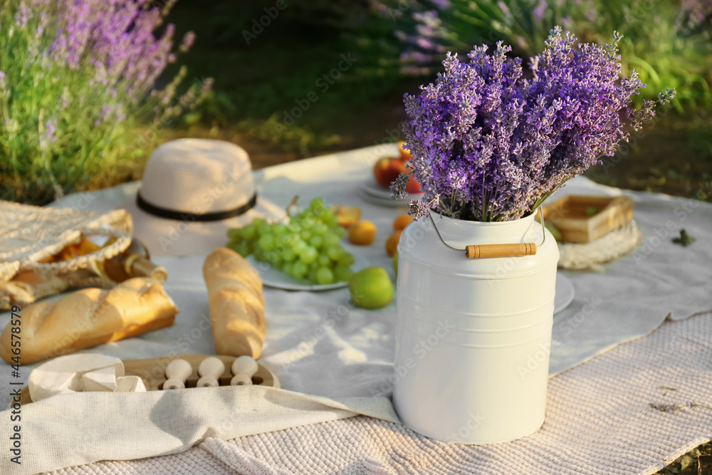 Pot with lavender flowers and tasty food for romantic picnic in lavender field - obrazy, fototapety, plakaty 