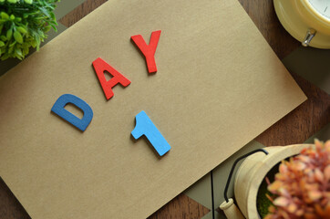 Aufkleber - Day 1, cover design in natural concept with the alphabet on brown notebook on the wooden table for a background.