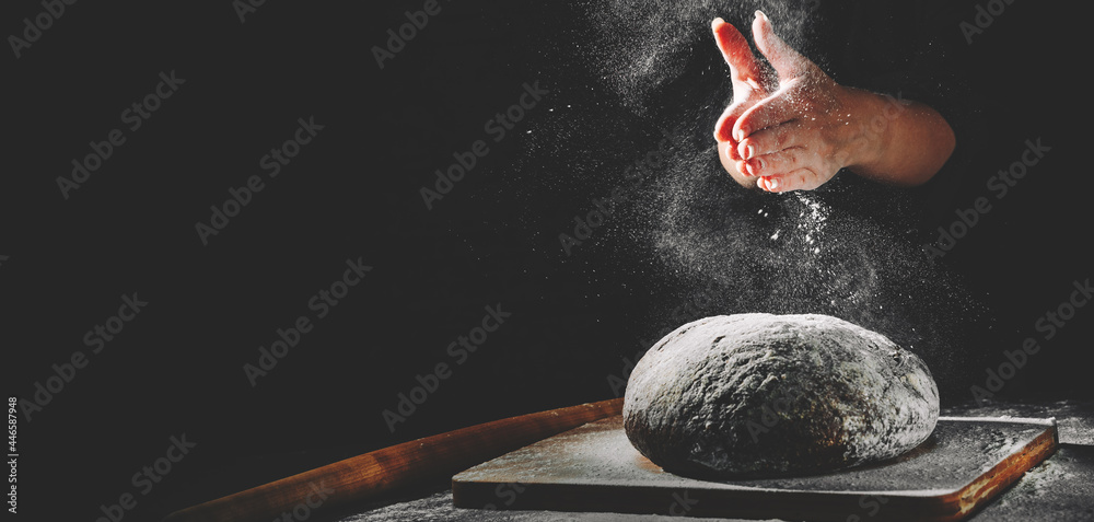 woman chef hand clap with splash of white flour and black background with copy space. woman's hands Making bread - obrazy, fototapety, plakaty 