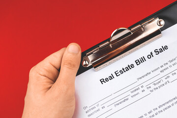 Wall Mural - Man hold real estate bill of sale form. Mortgage concept. Red background photo