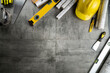 Contractor theme. Plans, tool kit of the contractor, yellow hardhat and libella. Gray tiles background.