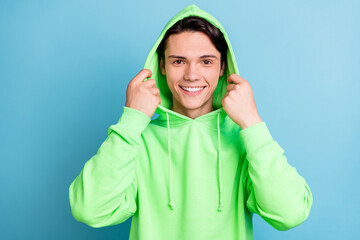 Poster - Photo of hipster funny guy hands hold hood white smile wear green sweatshirt isolated blue color background