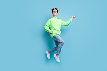 Canvas Print - Photo of pretty cool young guy dressed green hoodie jumping high playing guitar laughing smiling isolated blue color background