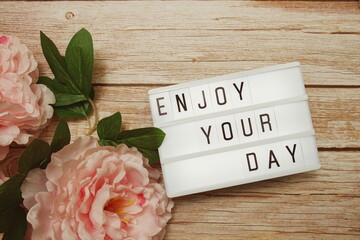 Wall Mural - enjoy your day text on lightbox on wooden background