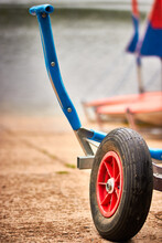 Closeup Of Red, Black And Blue Boat Launching Dolly Trailer Rubber Wheels On A Slipway With Red Dinghy Boats In The Background. Sailing Concept. Shallow Depth Of Field. Room For Copy Text.