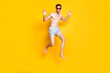 © deagreez - Photo of charismatic funky young man naked torso wear dark eyewear jumping high smiling isolated yellow color background