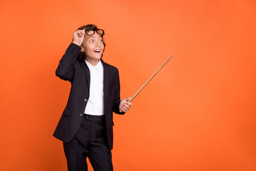 Sticker - Photo of young amazed shocked happy boy look empty space point stick isolated on orange color background