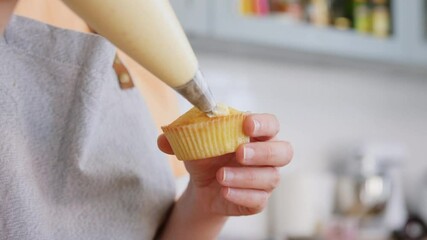 Wall Mural - culinary, bake and cooking food concept - young woman with baking bag making cupcake topping on kitchen at home