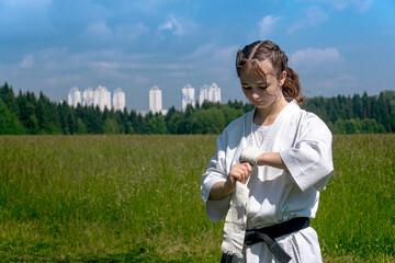 teenage girl in a kimono wrapping a wrist wrap around her hand before taking karate outdoors