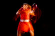 Front view of one professional male boxer in motion, action on black studio background in mixed lights.