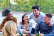 © MandriaPix - multiethnic group of university students having breakfast at the cafeteria, young friends smiling and laughing while drinking coffee and eating muffins