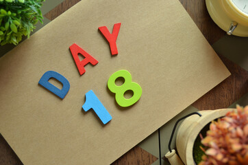 Aufkleber - Day 18, cover design in natural concept with the alphabet on brown notebook on the wooden table for a background.
