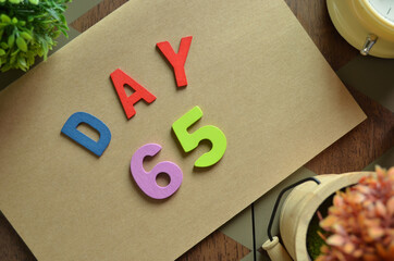 Aufkleber - Day 65, cover design in natural concept with the alphabet on brown notebook on the wooden table for a background.