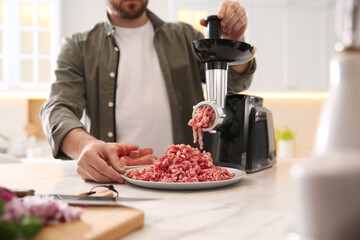 Canvas Print - Man using modern meat grinder in kitchen, closeup