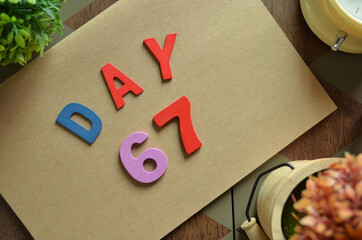 Aufkleber - Day 67, cover design in natural concept with the alphabet on brown notebook on the wooden table for a background.