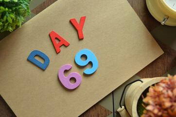 Aufkleber - Day 69, cover design in natural concept with the alphabet on brown notebook on the wooden table for a background.