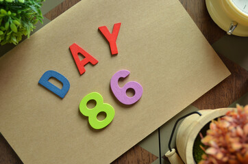 Aufkleber - Day 86, cover design in natural concept with the alphabet on brown notebook on the wooden table for a background.
