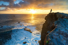 One Man Watching Sunrise Over The Ocean Waves From Cliffs, Madeira Island, Portugal