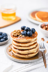 Wall Mural - Sweet breakfast pancakes with blueberries, walnuts and honey on a plate, closeup view