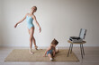 © Юлия Михайлова - an adult ballerina girl shows the movements of a little girl to a child who is sitting on the floor and learning