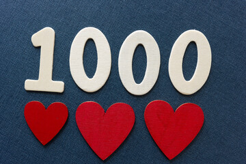 Sticker - the number 1000 in plain untreated die cut wooden numbers and red hearts on a dark blue background