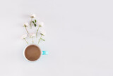 Fototapeta Storczyk - Coffee cup with white roses on light background. Creative office desk minimal concept with copy space. Lifestyle. Flat lay. Top view.
