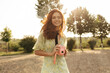 © Look! - Happy woman with red long hairstyle and lovely freckles in yellow summer outfit holding pink camera and smiling outdoor..