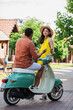 back view of african american man on scooter gesturing while talking to smiling asian woman