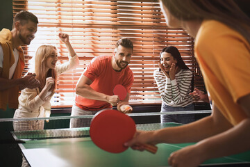 Wall Mural - Happy friends playing ping pong together indoors