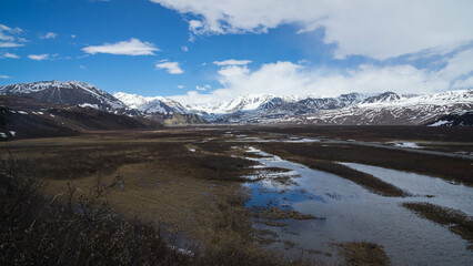 Sticker - Shallow river stream and a field - snowy hills in background