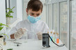© Anna - Young boy in protective clothing with pipette and special glass preparing for chemical experiences with microscope.