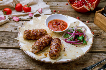 Canvas Print - Lamb Lula kebab with sliced onions and tomato sause on old wooden table