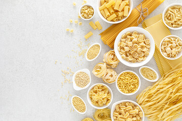 Poster - Pasta. Various kinds of uncooked pasta and noodles over stone background, top view with copy space for text. Italian food culinary concept. Collection of different raw pasta on cooking table