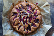 Round freshly baked plum cake on the wooden board