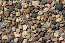 Top view close-up texture background of a vintage exposed aggregate stone patio surface in bright natural sunlight
